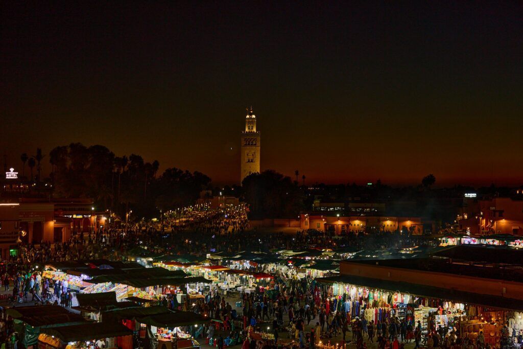 Vivi il vivace mercato notturno di Marrakech, Marocco, illuminato contro uno splendido cielo crepuscolare.