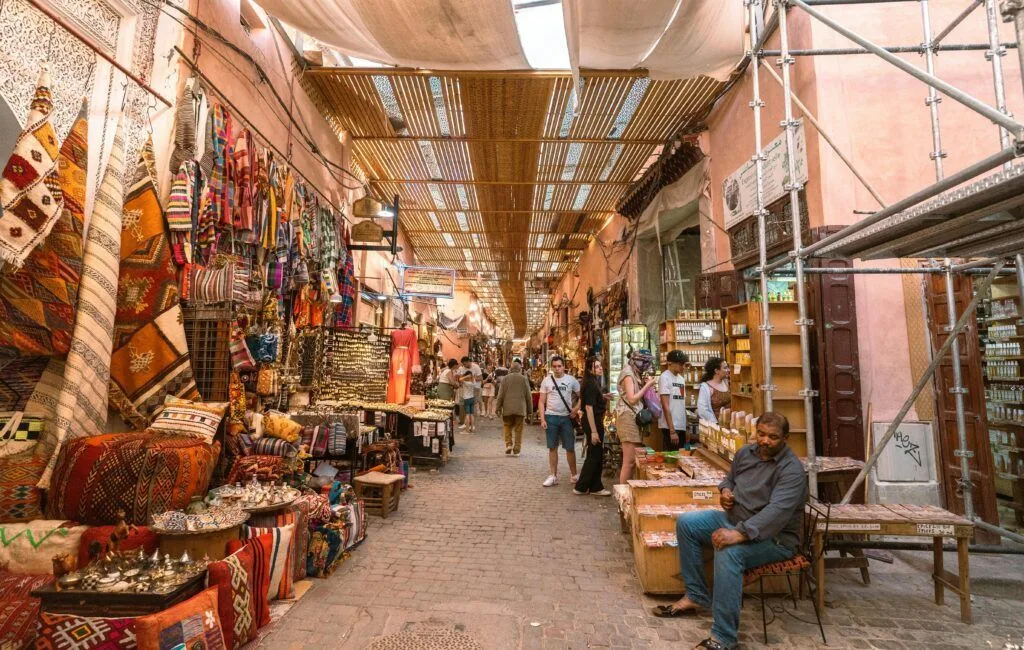 TOUR POR EL DESIERTO DEL SAHARA DESDE MARRAKECH (4 días) Explora los vibrantes colores y el animado ambiente de un zoco de Marrakech, mostrando artesanías tradicionales y cultura local.