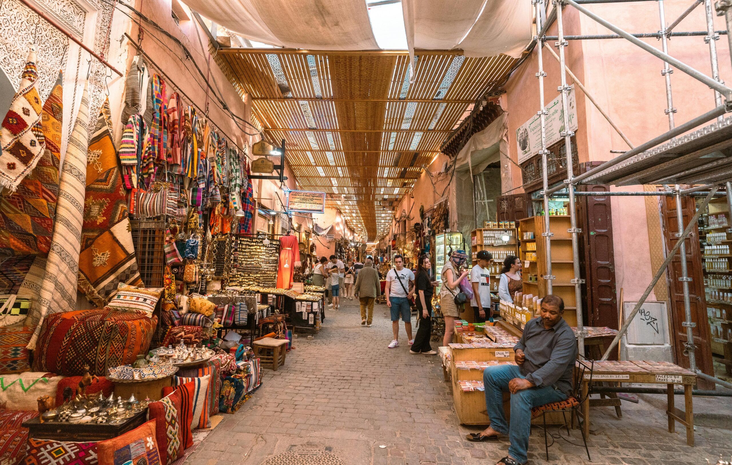 Fes to Marrakech (7 days) Explore the vibrant colors and lively atmosphere of a Marrakech souk, showcasing traditional crafts and local culture.