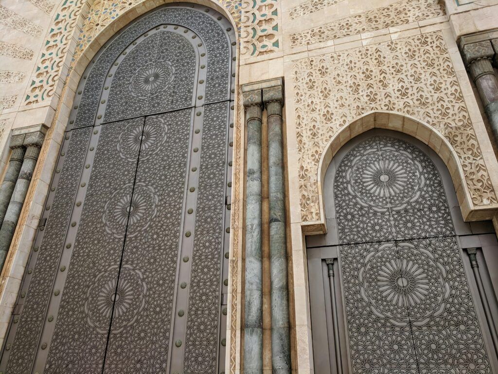 Le Città Imperiali del Marocco: Un Viaggio Attraverso Storia, Cultura e Vita Locale Primo piano di intricati motivi geometrici marocchini su una porta di moschea.