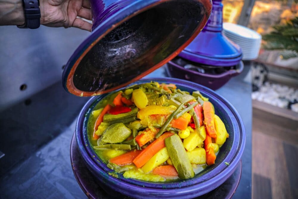 Moroccan Cooking Class Experience A colorful Moroccan tagine with fresh vegetables being uncovered, showcasing vibrant and healthy cuisine.