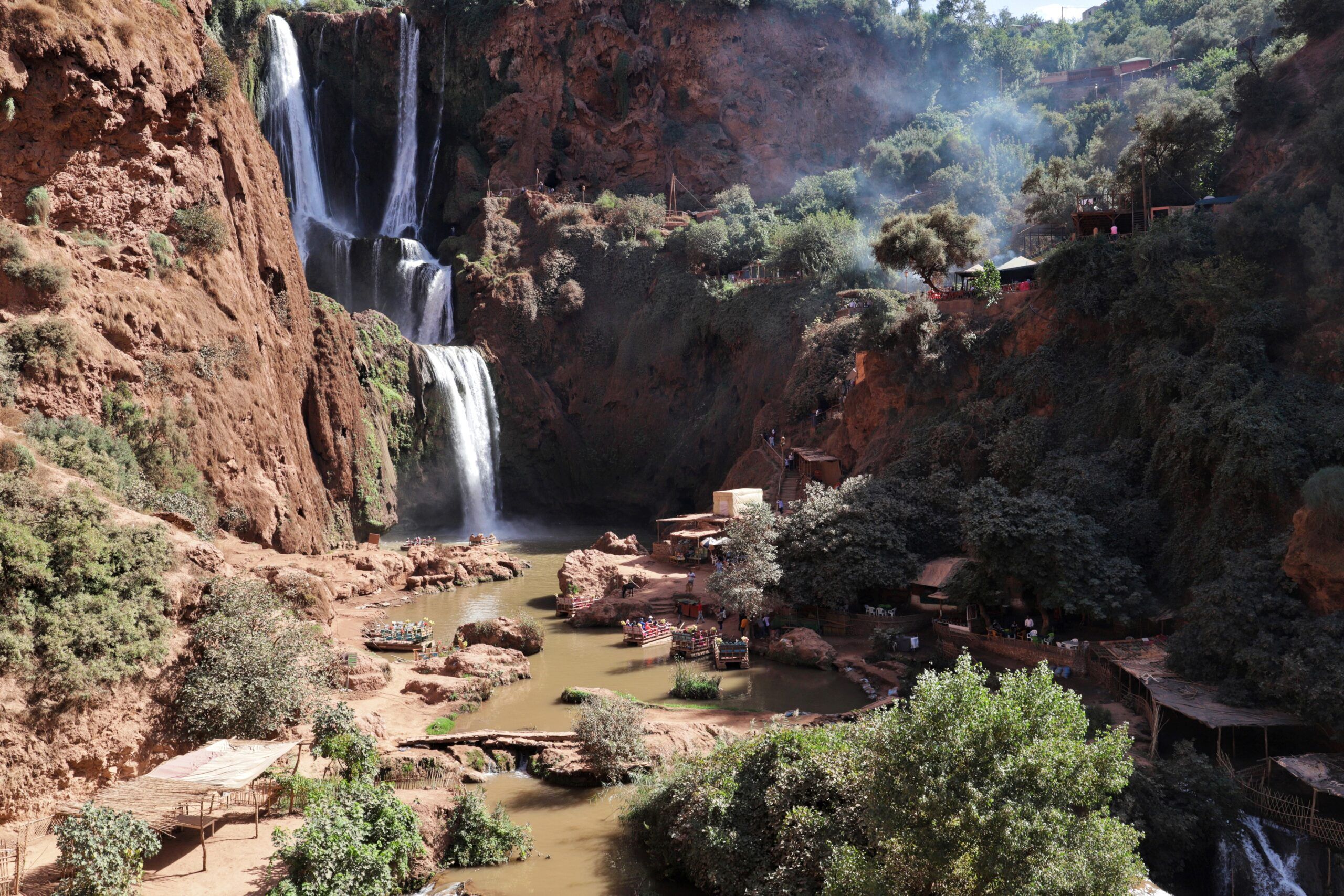 Stupefacente cascata che scorre tra scogliere rocciose circondate da una vegetazione vibrante in un tranquillo canyon.
